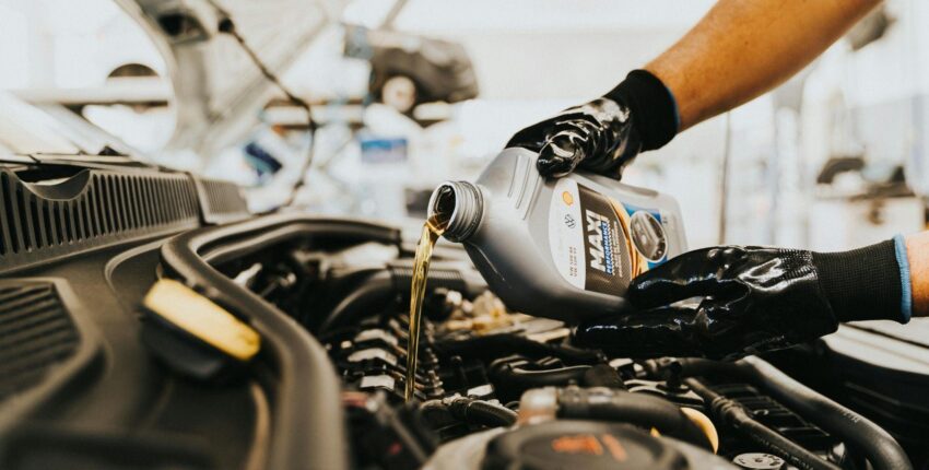 Mechanic pouring engine oil into vehicle